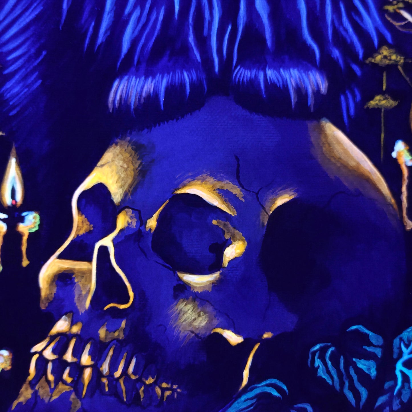 Blue and gold skull design with candles on a dark background